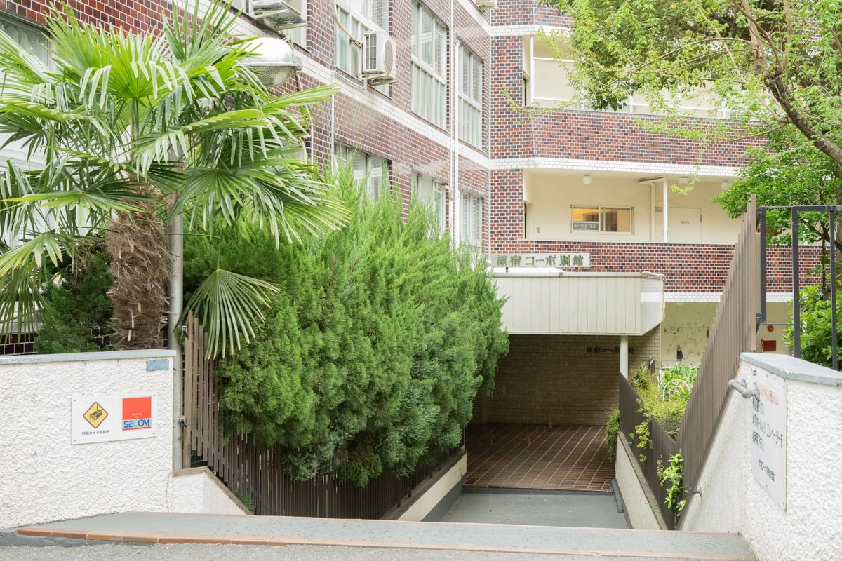 The building entrance with the “原宿コーポ別館” sign, down the walkway next to the planting